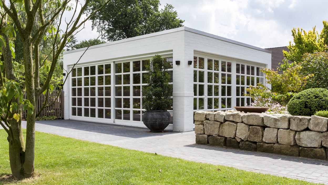 Bungalow mit Sprossenfenstern Weißer Bungalow mit Sprossenfenstern vor grüner Wiese