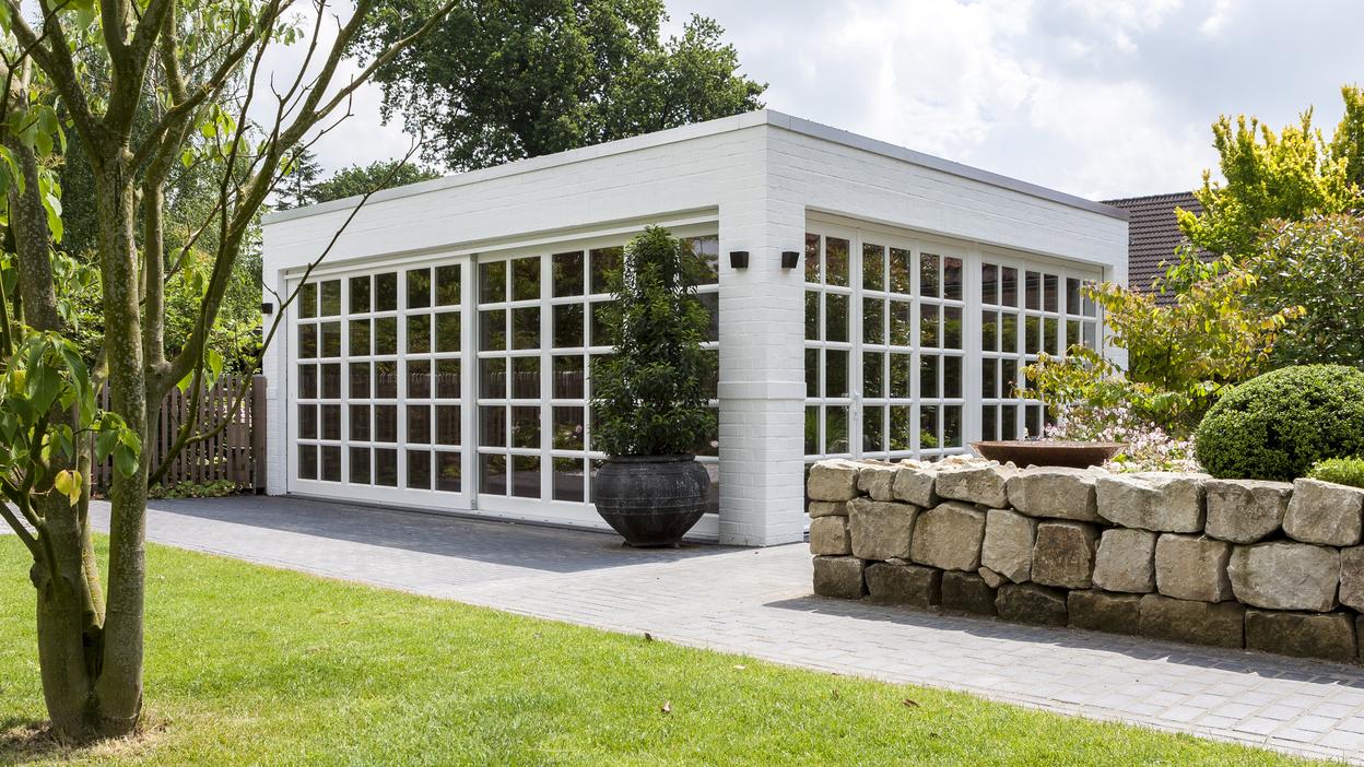 Bungalow mit Sprossenfenstern Weißer Bungalow mit Sprossenfenstern vor grüner Wiese